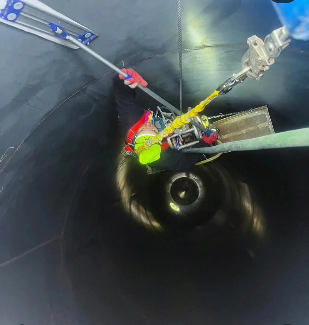 Worker in full safety harness and PPE working inside an industrial tank