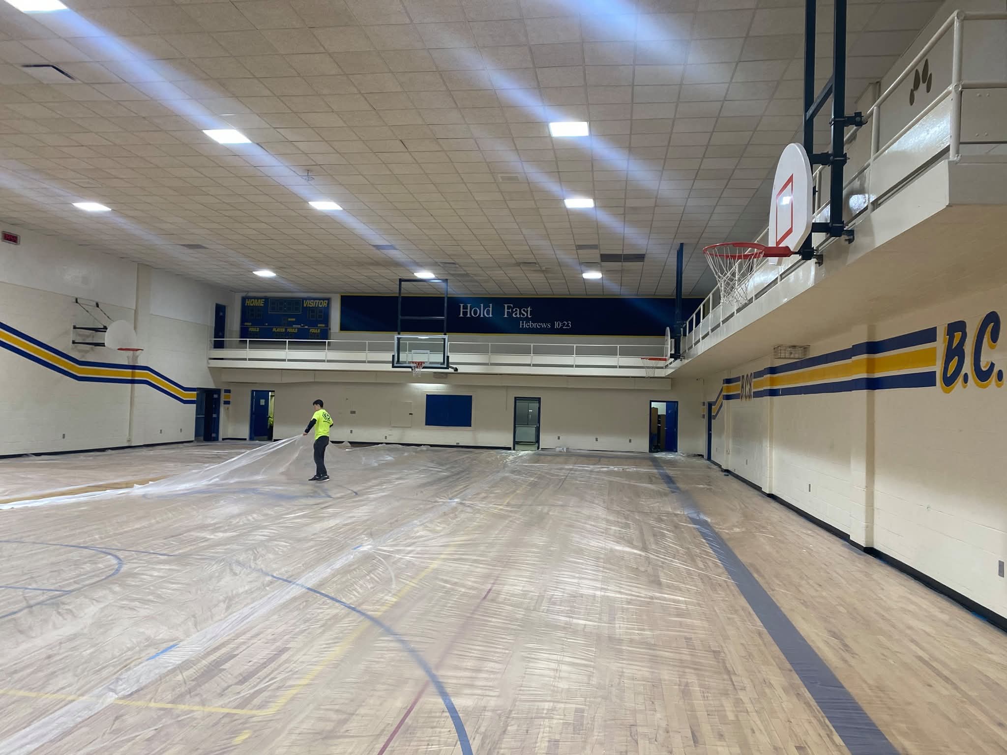 Crew working in the gymnasium with hardwood floor protected