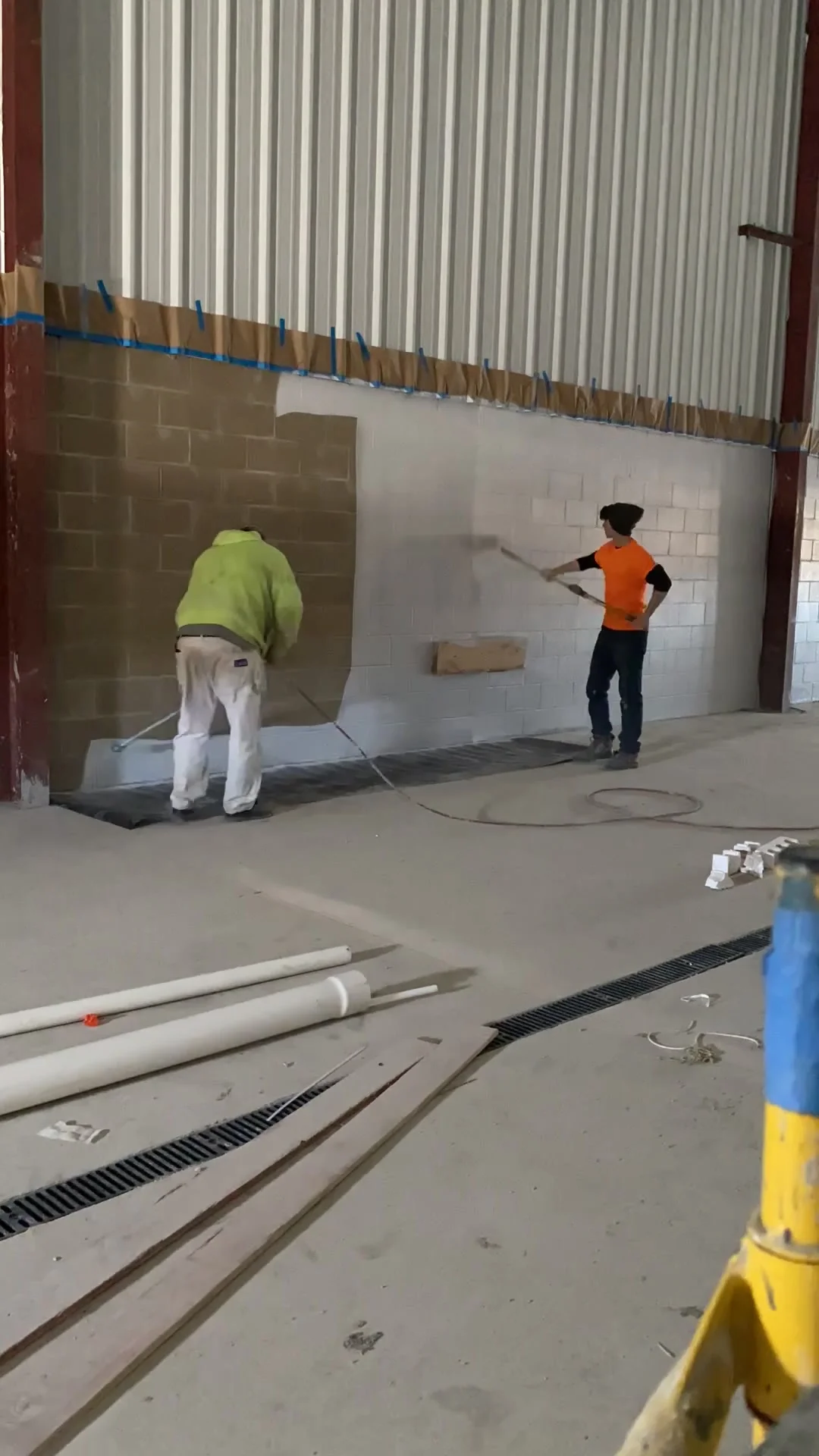 Crew working across the block wall — half filled, half bare, showing the clear transformation as work progresses