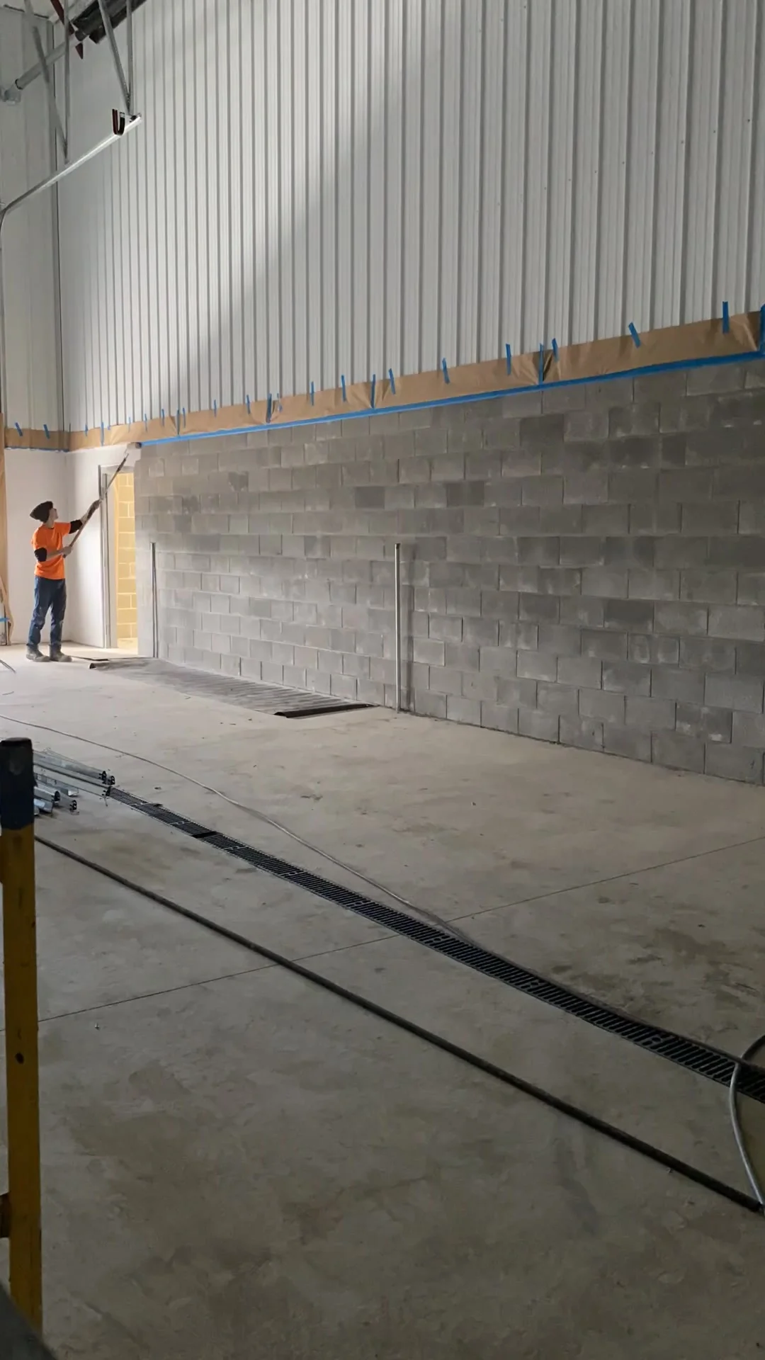 Wide shot of crew rolling block filler across the full length of the CMU wall