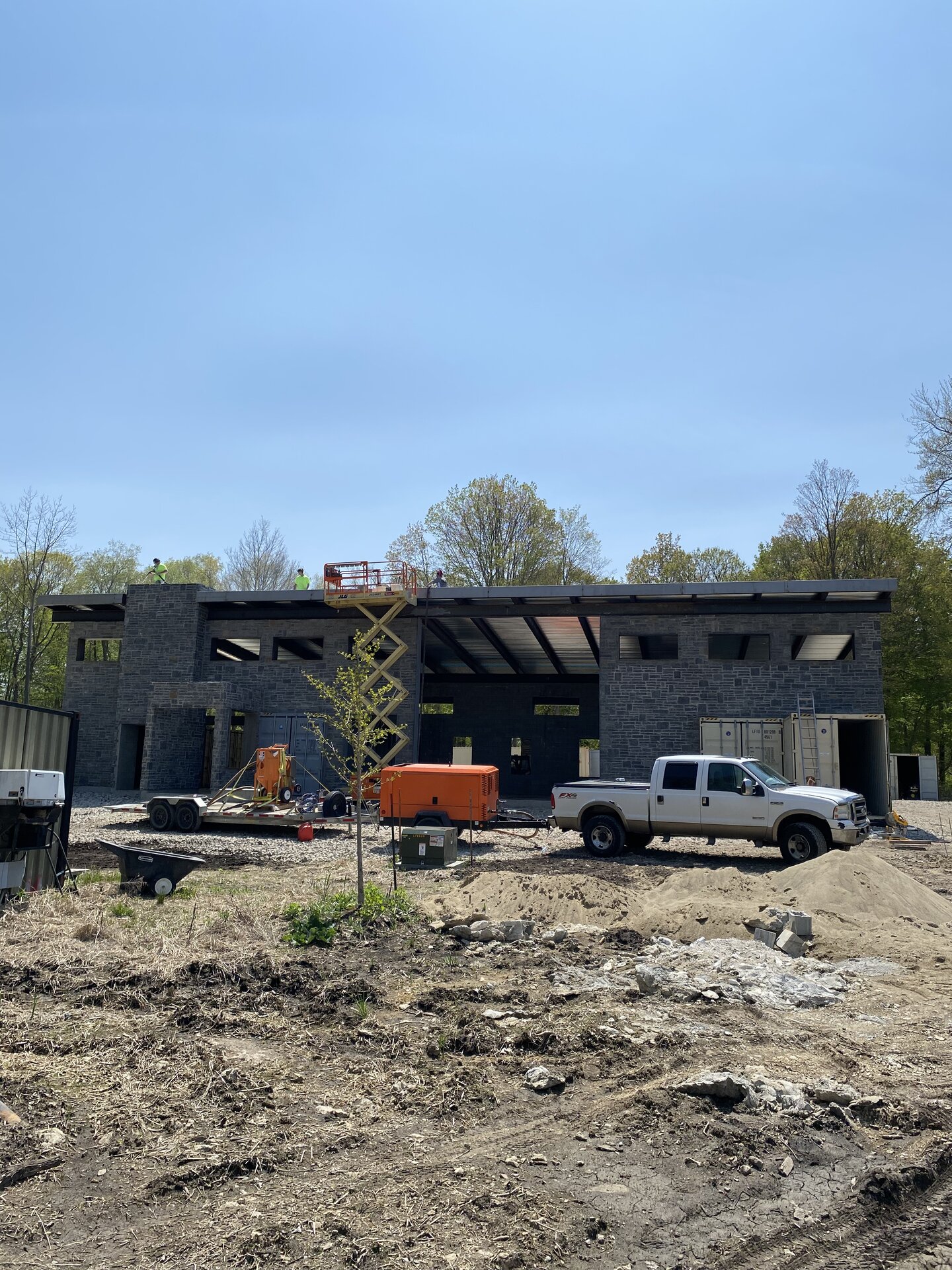 Early stage exterior — container house under construction with scissor lift