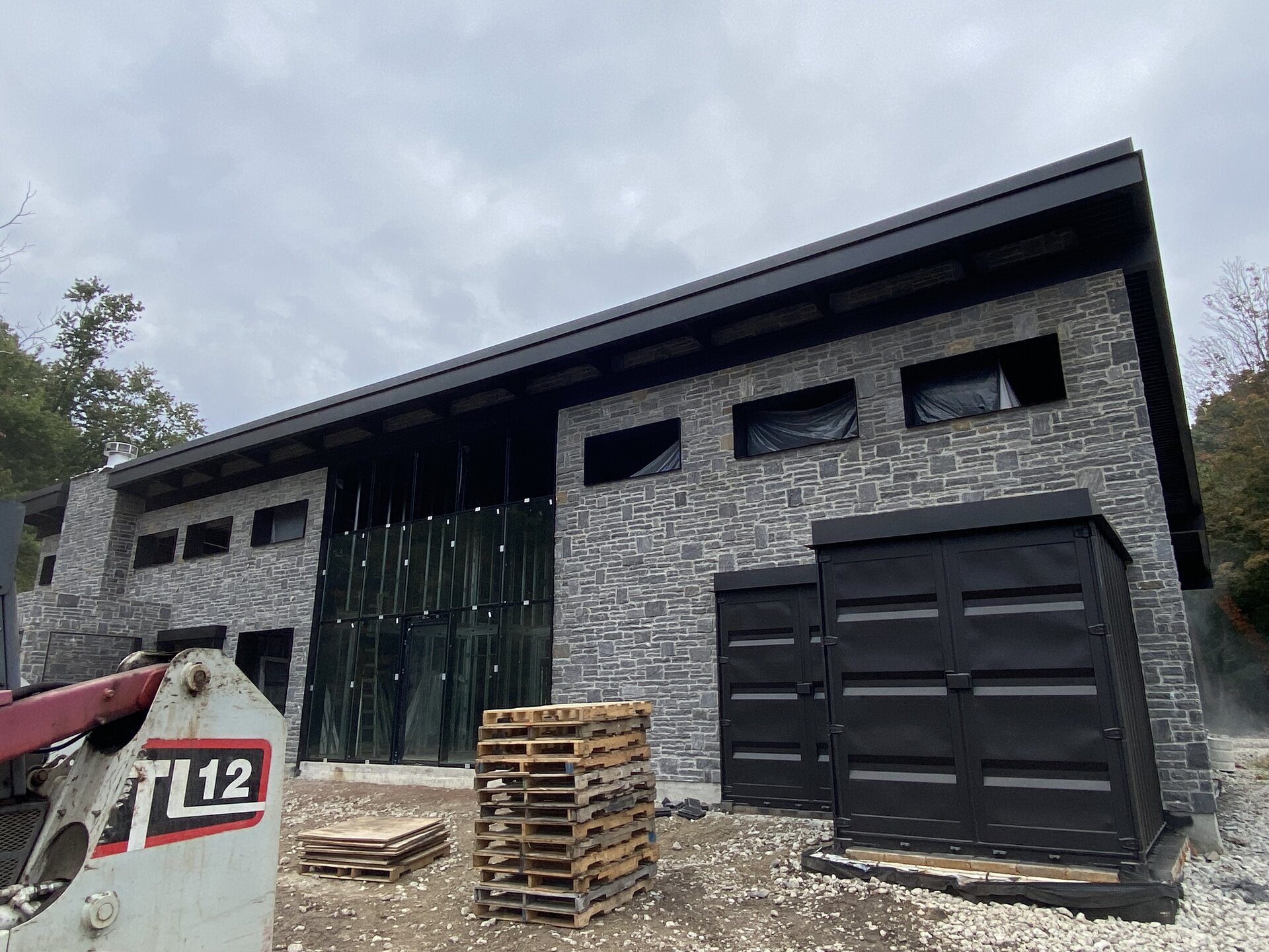 Painting a Container House — black-painted shipping containers and stone facade