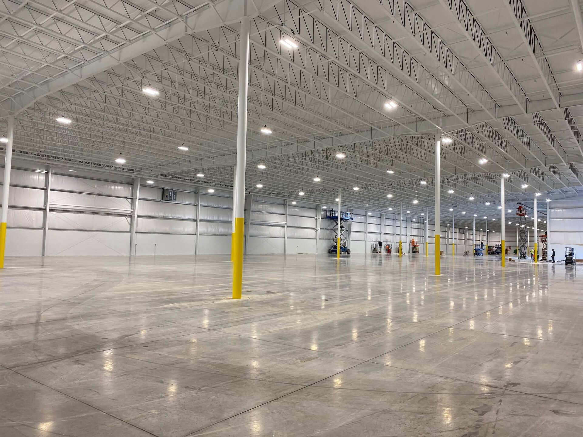 Completed interior view — white painted roof trusses, columns, and walls with yellow bollards