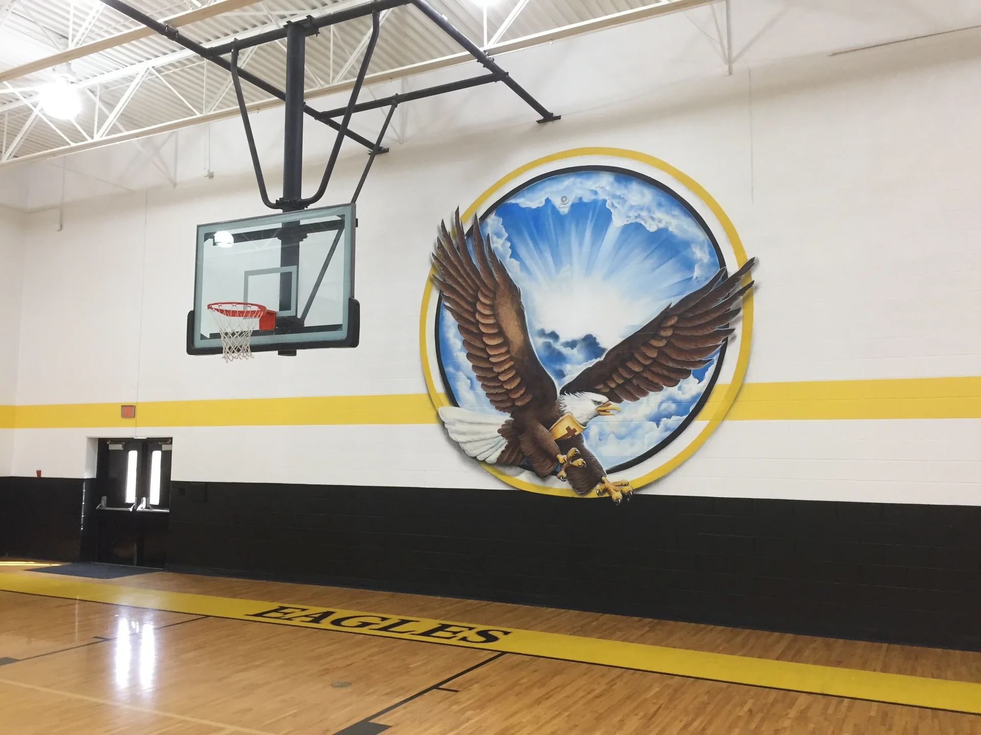 Eagles mascot mural close-up — detailed bald eagle in gold ring circle with EAGLES painted on the gymnasium floor