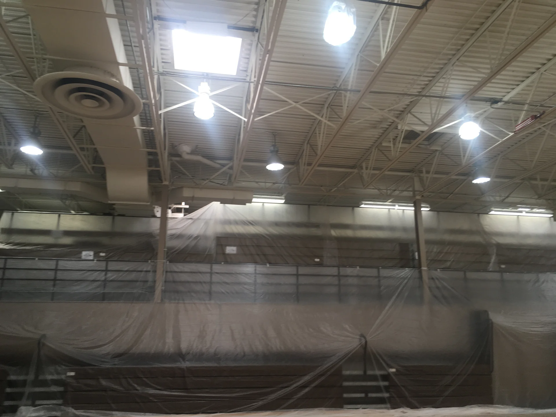 Before — full gymnasium with original walls, bleachers and floor fully protected for painting
