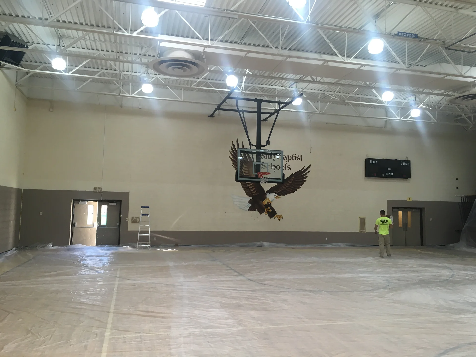 Endurance Painting crew at work — Faith Baptist Schools lettering and eagle mural visible on gymnasium wall