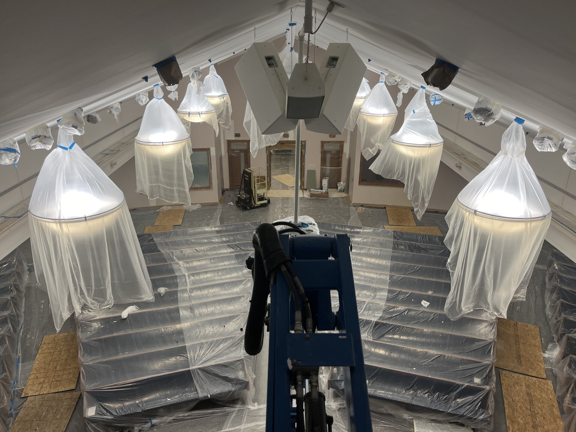 Sanctuary ceiling view from boom lift — chandeliers wrapped for protection