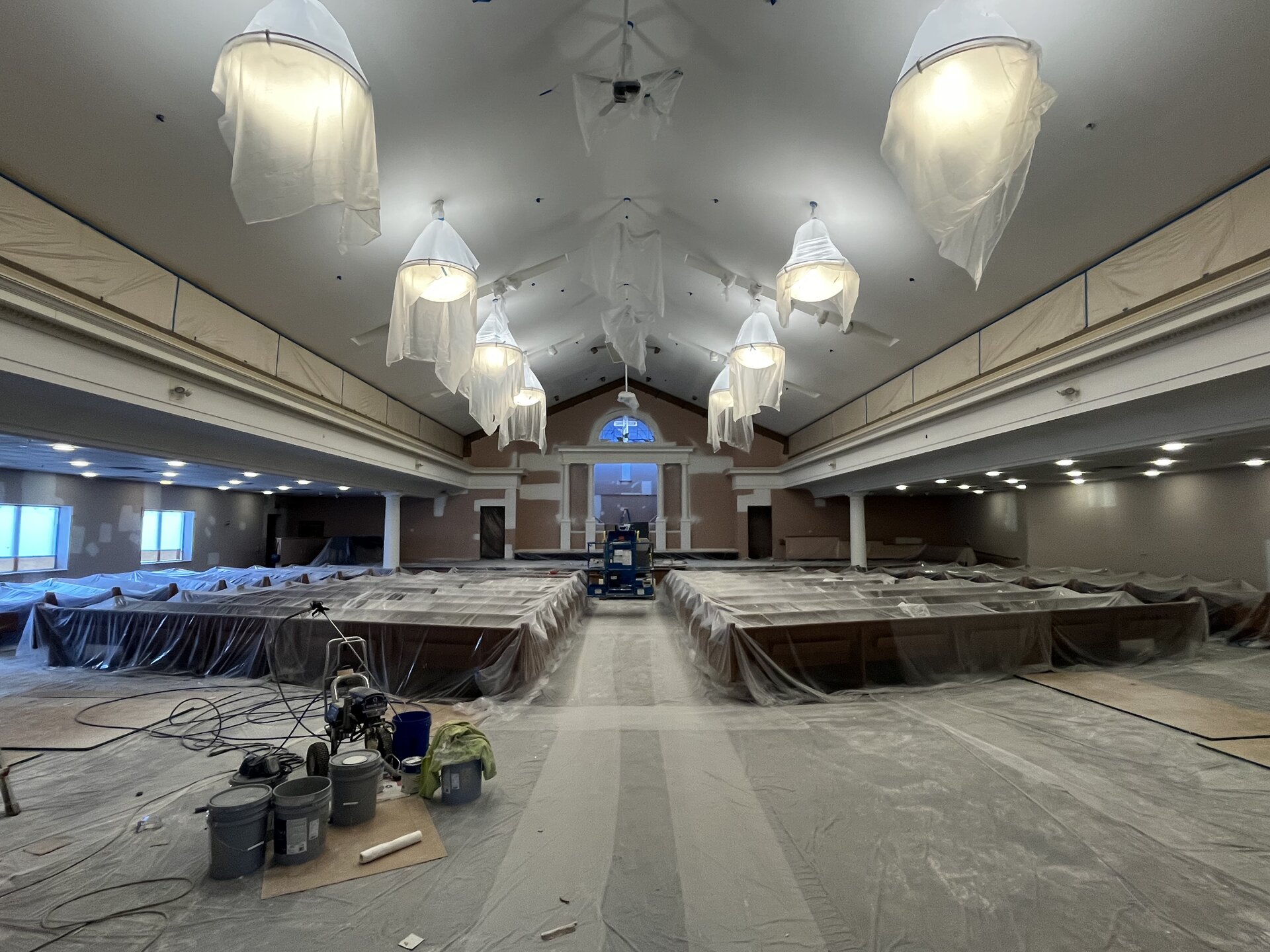 Church sanctuary during repaint — pews covered, equipment staged