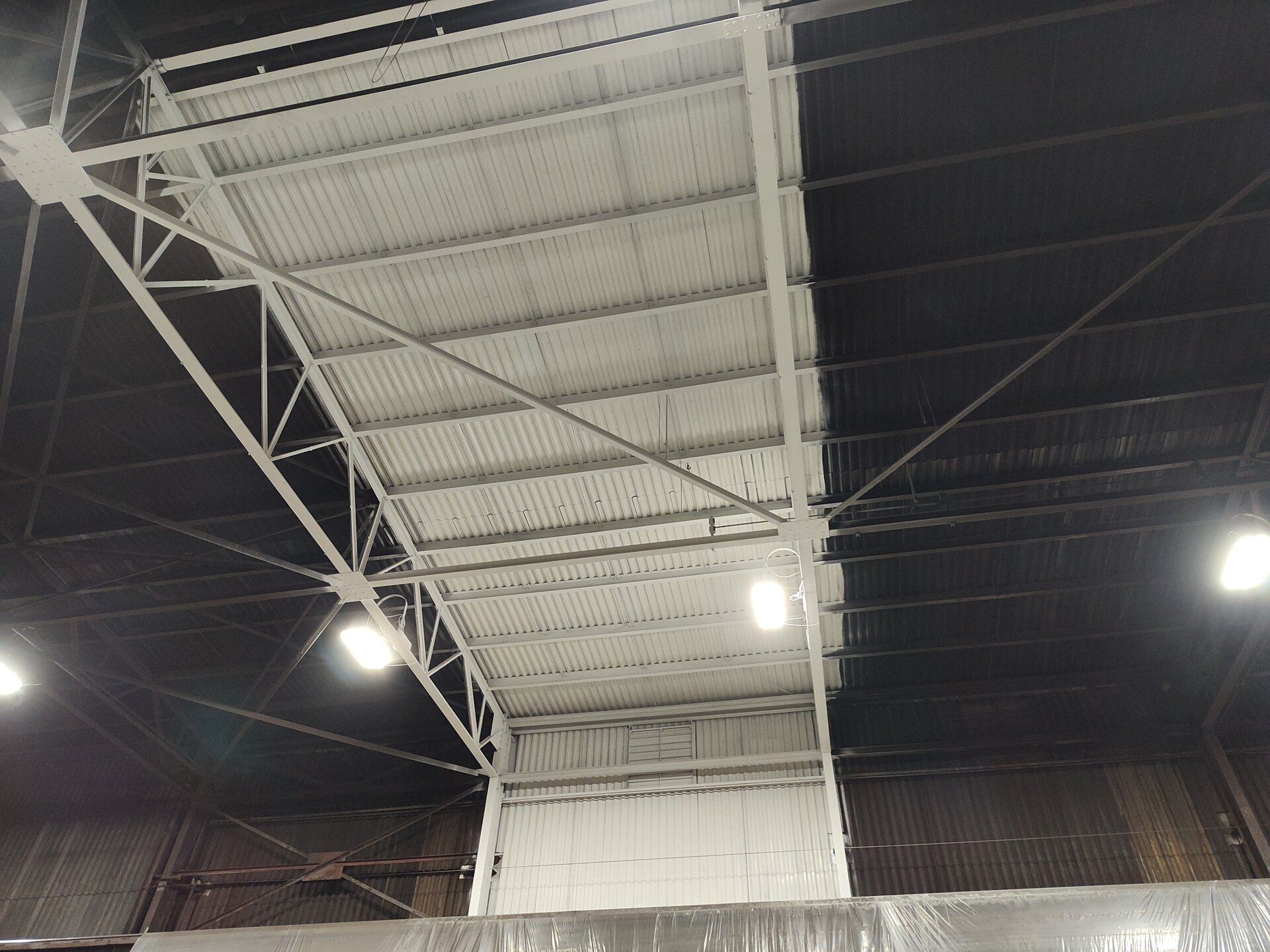 Freshly painted structural steel truss — dramatic contrast against decades of unpainted steel mill infrastructure