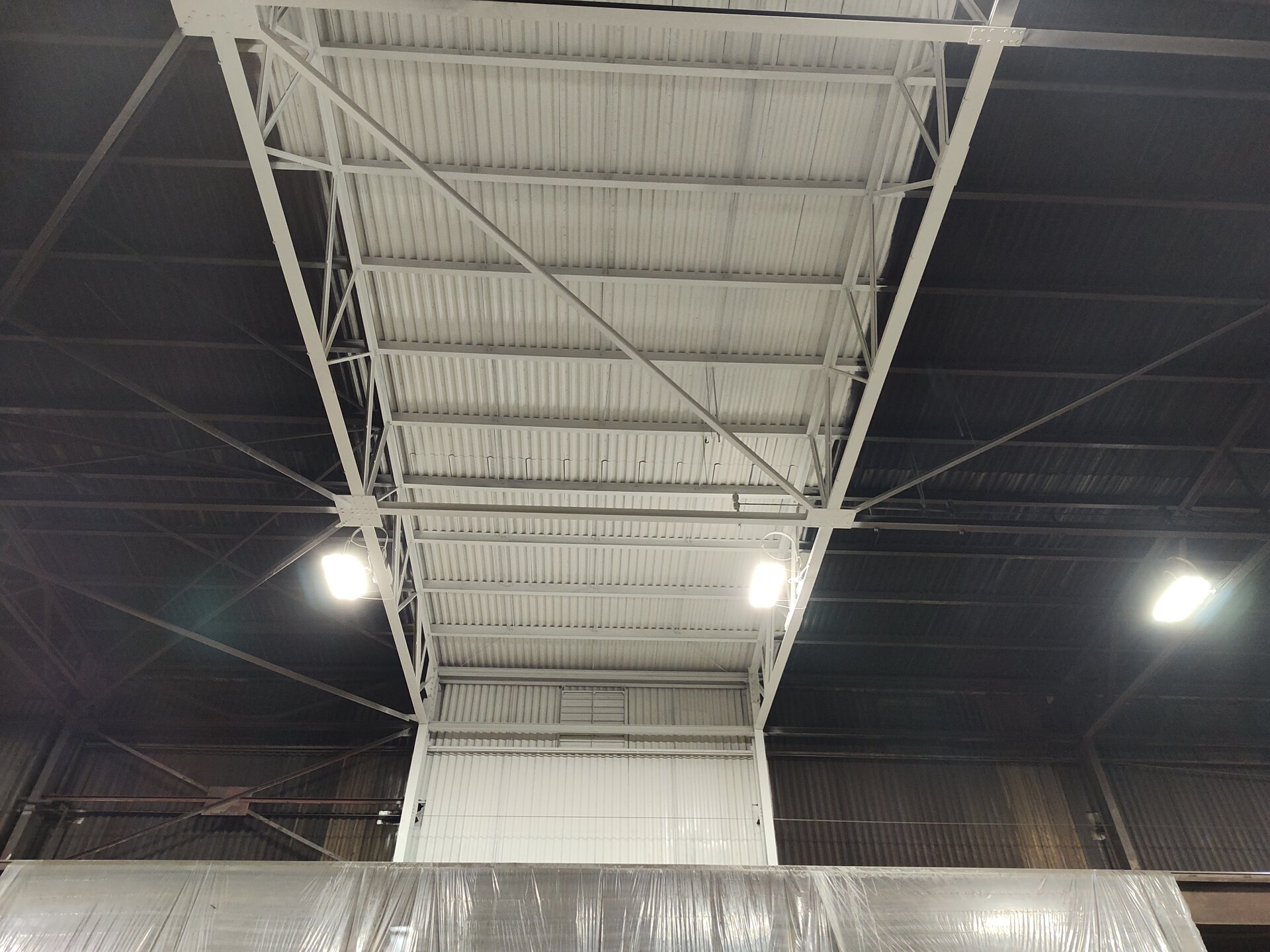 Steel mill interior paint sample — bright white coated section against uncoated dark structure