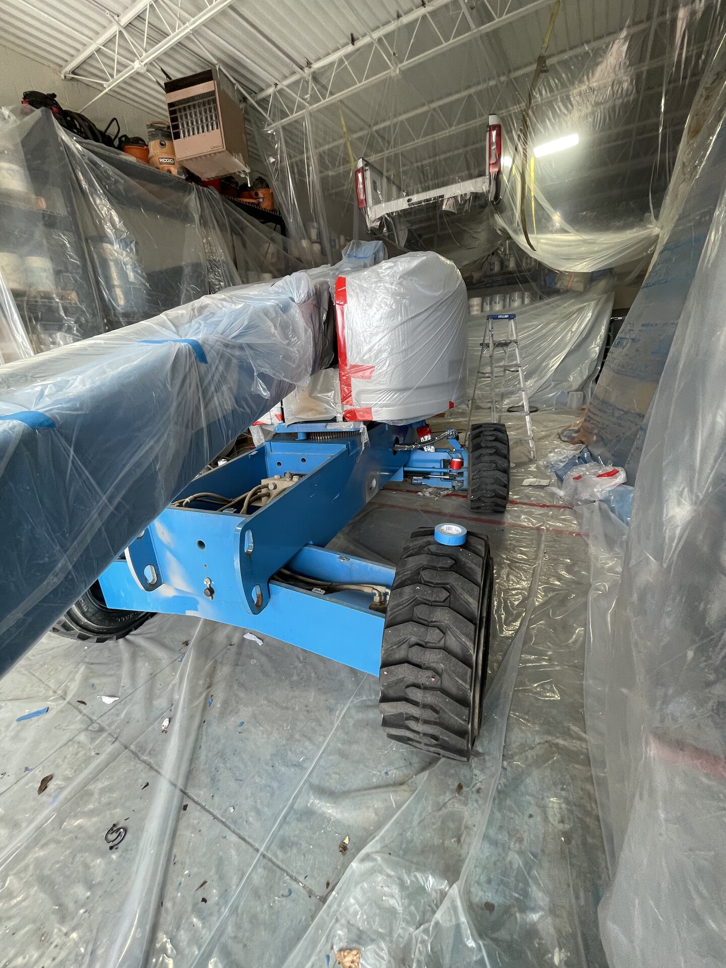 McCallister boom lift mid-repaint — masking in place, fresh coat being applied