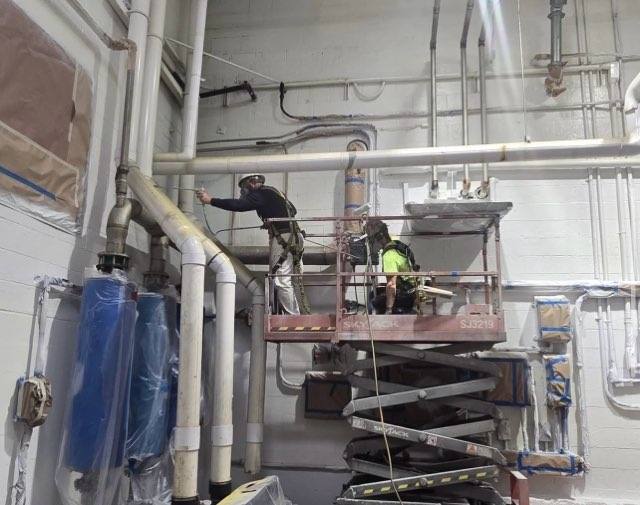 EP crew on scissor lift painting upper walls and pipes